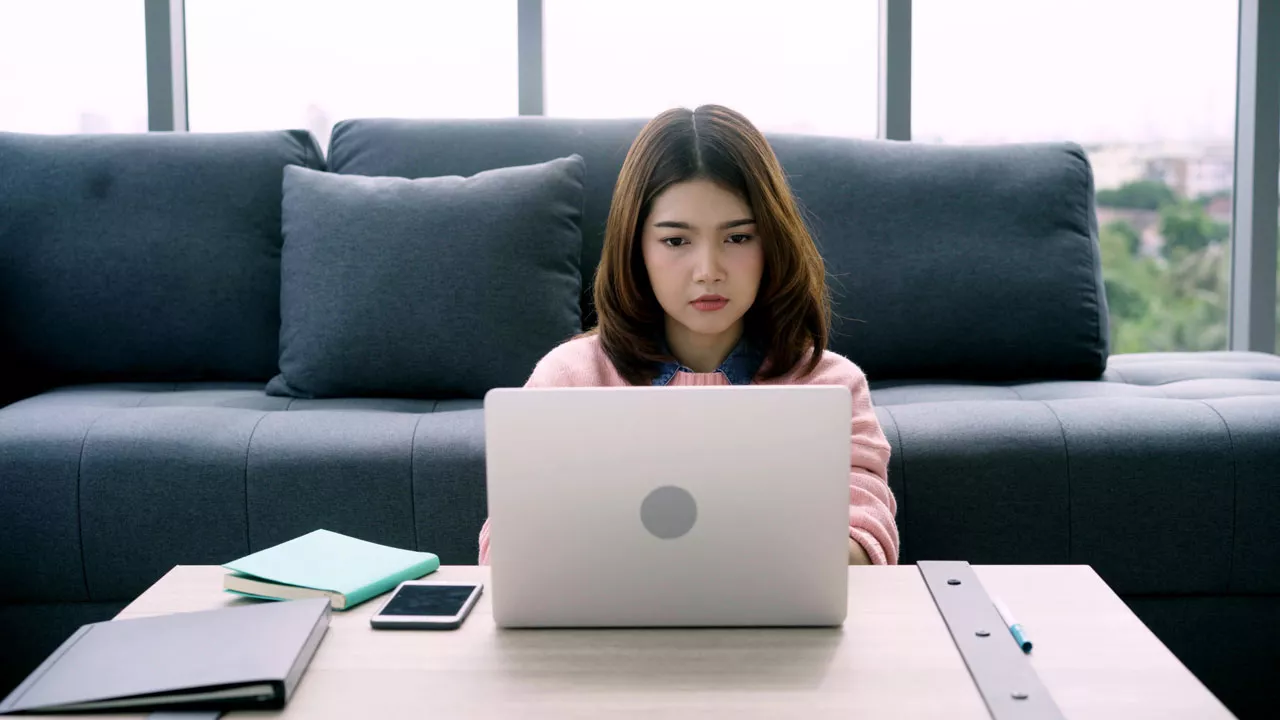 Mujer frente a un computador realizando una compra online con cara de preocupación