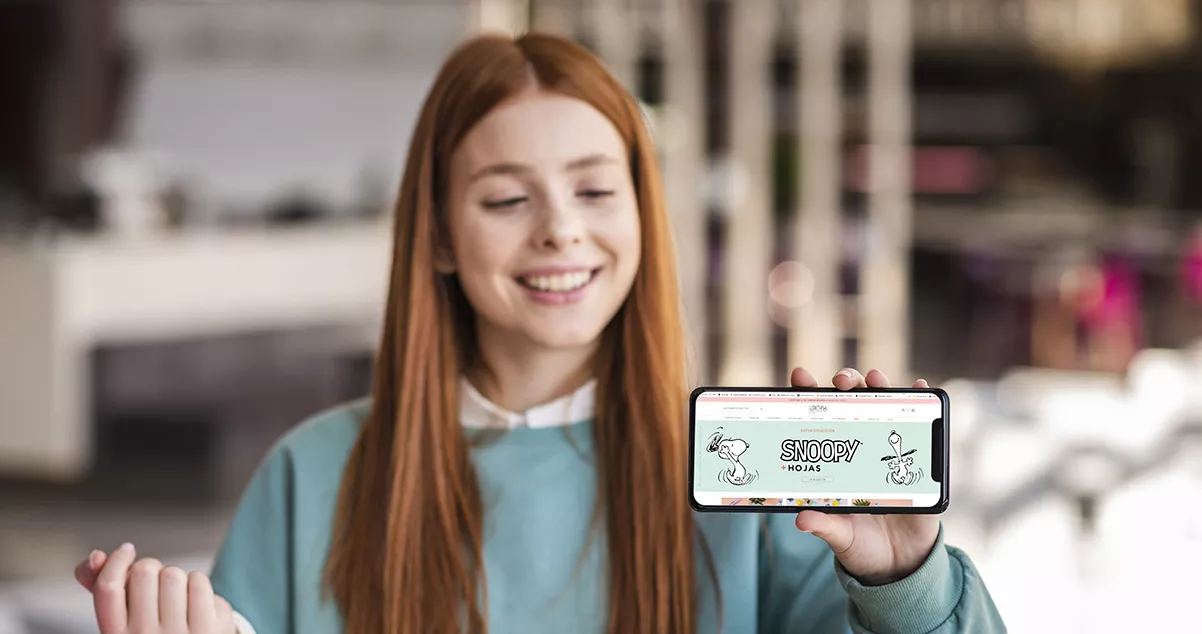 Imagen de una chica con un celular en la mano mostrando una tienda virtual en la pantalla - WebKreativo