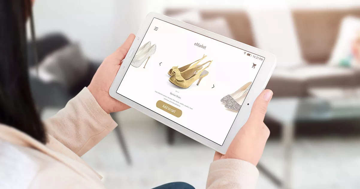 Mujer mirando zapatos en una tienda virtual en una Tablet para ilustrar desventajas del ecommerce, como por ejemplo, la imposibilidad de probar el producto antes de ordenar